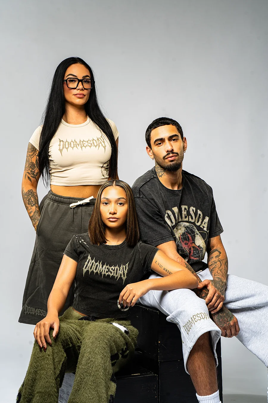 Three models wearing DOOMESDAY cropped tees, a graphic tee, and shorts from the Survive.The.Day studio session.